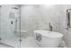 Modern bathroom featuring a soaking tub, glass-enclosed shower, and elegant marble tiling at 16316 Silent Sands Ln, Odessa, FL 33556