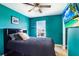 Cozy bedroom featuring a dark bed set, turquoise walls and a mounted flat screen TV at 16316 Silent Sands Ln, Odessa, FL 33556