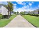 A peaceful walkway is adorned with manicured hedges and swaying palm trees, creating a serene neighborhood setting at 16316 Silent Sands Ln, Odessa, FL 33556