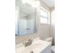 Bathroom featuring a white vanity, large mirror, window, and a shower with white tile at 1766 10Th Sw St, Largo, FL 33778