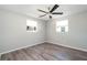 Neutral bedroom with gray laminate flooring, modern ceiling fan, and two large windows at 1766 10Th Sw St, Largo, FL 33778