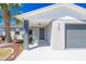 Close up of home's front door and attached garage; gray paint, white trim, manicured landscaping, and modern design at 1766 10Th Sw St, Largo, FL 33778