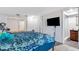 Bedroom with TV, closet, and blue patterned bed, leading to an adjacent bathroom with a shower at 1988 58Th N St, St Petersburg, FL 33710