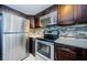 Modern kitchen with stainless steel appliances, dark wood cabinets, and tile backsplash at 2571 Cyprus Dr # 1-105, Palm Harbor, FL 34684