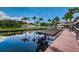Waterfront boat dock with a boat parked in front of a pool surrounded by tropical palm trees at 2571 Cyprus Dr # 1-105, Palm Harbor, FL 34684
