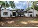 Charming white brick home featuring black trim, dormer windows, mature landscaping, and a welcoming front entrance at 2715 Willow Oaks Dr, Valrico, FL 33594