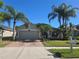 Inviting single-story home with lush landscaping, including palm trees, and a brick driveway leading to a two-car garage at 31150 Harthorn Ct, Wesley Chapel, FL 33543