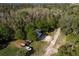 Aerial view showcasing the property with lush greenery, gravel driveway, and surrounding wooded areas at 317 Old East Lake Rd, Tarpon Springs, FL 34688