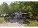 Aerial view of a home's exterior with a carport and a gravel driveway surrounded by lush trees at 317 Old East Lake Rd, Tarpon Springs, FL 34688