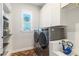 Well-equipped laundry room with modern washer and dryer, storage cabinets, and sink at 4117 W Platt St, Tampa, FL 33609