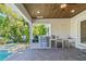 An outdoor kitchen with stainless steel appliances complements a large brick patio with a pool and greenery at 4117 W Platt St, Tampa, FL 33609