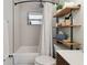 Charming bathroom featuring a shower-tub combo and open wooden shelves for storage at 4126 Harrisburg Ne St, St Petersburg, FL 33703