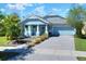 Charming, light blue single-Gathering home featuring a brick driveway, manicured landscaping, and a welcoming front porch at 5128 Admiral Pointe Dr, Apollo Beach, FL 33572