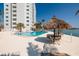 Serene pool area with lounge chairs, a tiki umbrella, and palm trees next to the apartment building at 7200 Sunshine Skyway S Ln # 3D, St Petersburg, FL 33711