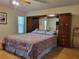 Spacious bedroom with wood floors, a large headboard, and abundant natural light from the windows at 7392 Meadow Brook Ln, Spring Hill, FL 34606