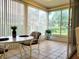 Enclosed sunroom with tile flooring, bright windows with vertical blinds, and a table set for two at 7392 Meadow Brook Ln, Spring Hill, FL 34606