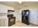 Efficient kitchen includes white cabinets, black appliances, wood-look flooring, and a side-by-side refrigerator at 7509 Mesa St, North Port, FL 34287