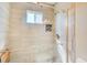 This is a shower with light grey tile, a glass door, and a small window at 7509 Mesa St, North Port, FL 34287