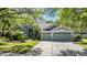 Charming gray home showcasing a three-car garage, tiled roof, well-manicured lawn and tropical landscaping at 9302 Deer Creek Dr, Tampa, FL 33647