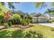 Beautifully landscaped single-story home with gray siding, a tile roof, and a two-car garage at 9302 Deer Creek Dr, Tampa, FL 33647