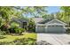 Charming gray home showcasing a three-car garage, tiled roof, well-manicured lawn and tropical landscaping at 9302 Deer Creek Dr, Tampa, FL 33647