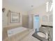 Bathroom featuring a soaking tub and glass-enclosed shower, along with a granite vanity, for a spa-like atmosphere at 9711 Wydella St, Riverview, FL 33569