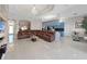 Bright living room with tile flooring, chandelier, and a brown leather sectional sofa, adjacent to kitchen at 9711 Wydella St, Riverview, FL 33569