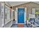 Charming front porch with a blue door, 'Welcome' mat, seating, and decorative plants at 10404 Hawk Ct, Riverview, FL 33578