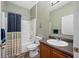 Cozy bathroom featuring a shower with blue curtain, toilet, vanity with granite countertop, and wall decor at 12442 Curry Dr, Spring Hill, FL 34609