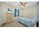Bright bedroom with ceiling fan, dresser, window with blue curtain, and a cozy bed with decorative seashell pattern covers at 12442 Curry Dr, Spring Hill, FL 34609