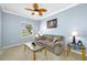 Cozy living room with comfortable seating, a ceiling fan, and natural light from the window at 12442 Curry Dr, Spring Hill, FL 34609