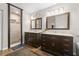 Bathroom with dual vanities, modern lighting, dark wood cabinets and a frameless glass shower at 12929 Prestwick Dr, Riverview, FL 33579