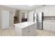 Bright kitchen features an island with white marble countertops, stainless steel refrigerator, and white cabinets at 12929 Prestwick Dr, Riverview, FL 33579