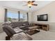 Inviting living room with a leather sectional, ceiling fan, large windows, and a flat screen television at 12929 Prestwick Dr, Riverview, FL 33579
