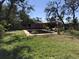 Backyard view of the in-ground pool with mature trees and lush landscaping at 1465 Fundy Rd, Venice, FL 34293