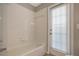 White bathroom featuring a tub, a shower head and a door leading outside at 14659 Banana Tree Ln, Clearwater, FL 33760