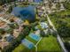 Aerial view showcasing community amenities: tennis courts, basketball court, pool, playground and lake, all amid lush greenery at 15925 Pond Rush Ct, Land O Lakes, FL 34638