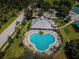 Aerial view of community pool with palm trees, lounge chairs, tables, tennis courts and clubhouse at 15925 Pond Rush Ct, Land O Lakes, FL 34638