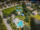 Aerial view of community pool with palm trees, tennis courts, playground and a pond at 15925 Pond Rush Ct, Land O Lakes, FL 34638