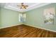 Spacious bedroom featuring wood floors, tray ceiling with fan, and plenty of natural light at 15925 Pond Rush Ct, Land O Lakes, FL 34638