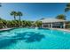 Community pool with fountain feature, palm trees, lounge chairs, and clubhouse with metal roof at 15925 Pond Rush Ct, Land O Lakes, FL 34638
