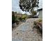 Backyard stone paver path, bordered by potted plants and greenery, leading to a fenced yard at 1731 W Perio St, Tampa, FL 33612
