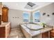 Light filled bathroom with a soaking tub, wood cabinets and a view to the water through a large picture window at 200 Driftwood W Dr, Palm Harbor, FL 34683