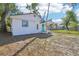 Delightful white home with a vibrant blue door and a cozy front porch, surrounded by lush greenery at 2111 E Ellicott St, Tampa, FL 33610