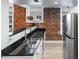 Kitchen featuring black granite countertops, stainless steel appliances, brick wall, and hardwood floors at 215 Central Ave # 4H, St Petersburg, FL 33701