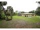 Expansive backyard featuring a well-maintained lawn, mature trees, and a screened lanai for outdoor enjoyment at 229 Tazewell Dr, Port Charlotte, FL 33954