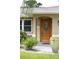 Close up of Front Door with decorative wooden door, pot with plants and well maintained landscaping at 229 Tazewell Dr, Port Charlotte, FL 33954