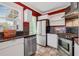 Kitchen view featuring stainless steel appliances, range hood, dark countertops, and a window at 3000 2Nd N Ave, St Petersburg, FL 33713