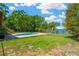 Private backyard with a pool, lush lawn, and a patio under a bright blue sky at 37451 Hickory Hill Ln, Dade City, FL 33525