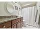 Well-lit bathroom featuring granite countertop, round mirror, and shower with white textured curtain at 3952 Applegate Cir, Brandon, FL 33511